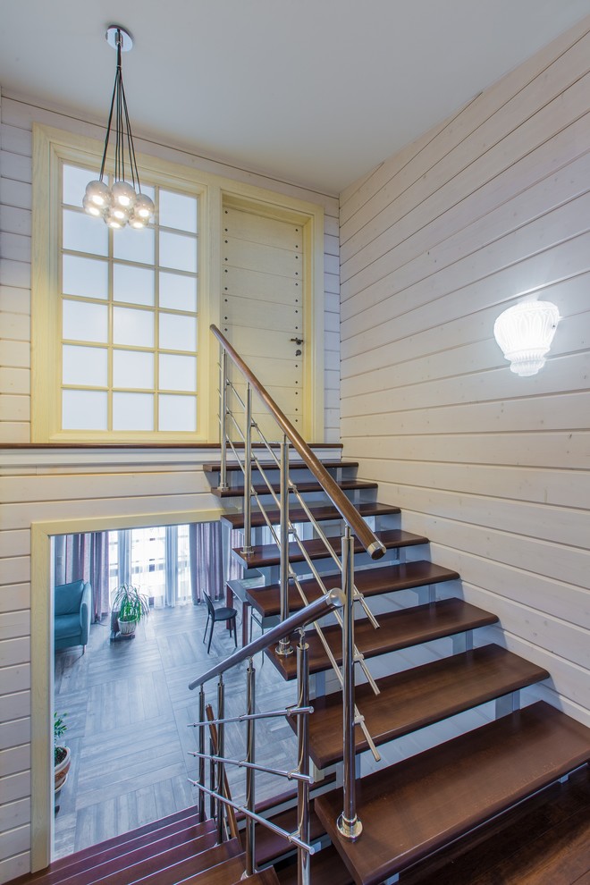 На фото: п-образная лестница в современном стиле с деревянными ступенями и перилами из смешанных материалов без подступенок с