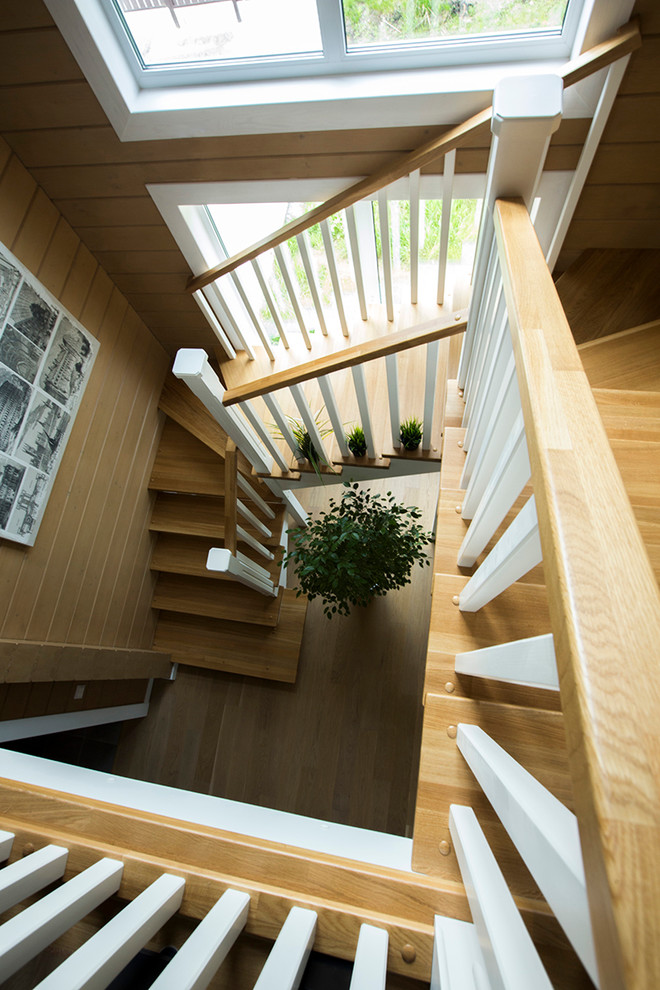 Идея дизайна: изогнутая лестница в стиле кантри с деревянными ступенями без подступенок