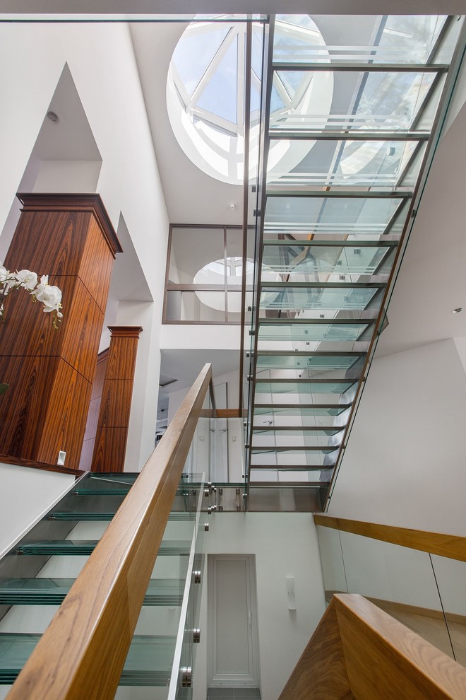 На фото: п-образная лестница в современном стиле с стеклянными ступенями и перилами из смешанных материалов без подступенок с