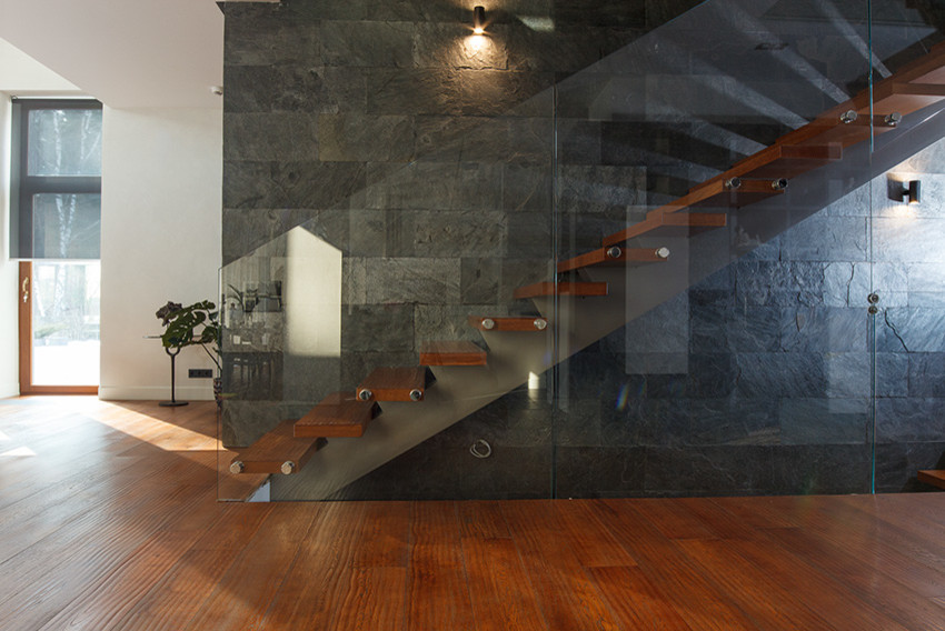 Exempel på en modern rak trappa i målat trä, med öppna sättsteg och räcke i glas