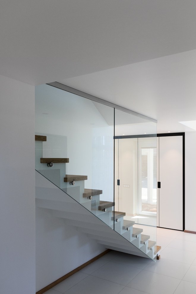 Стильный дизайн: прямая лестница с деревянными ступенями, подступенками из плитки и стеклянными перилами - последний тренд