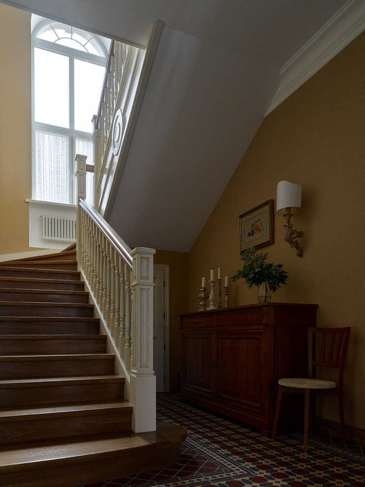 Ejemplo de escalera clásica grande con escalones de madera, contrahuellas de madera, barandilla de madera y papel pintado