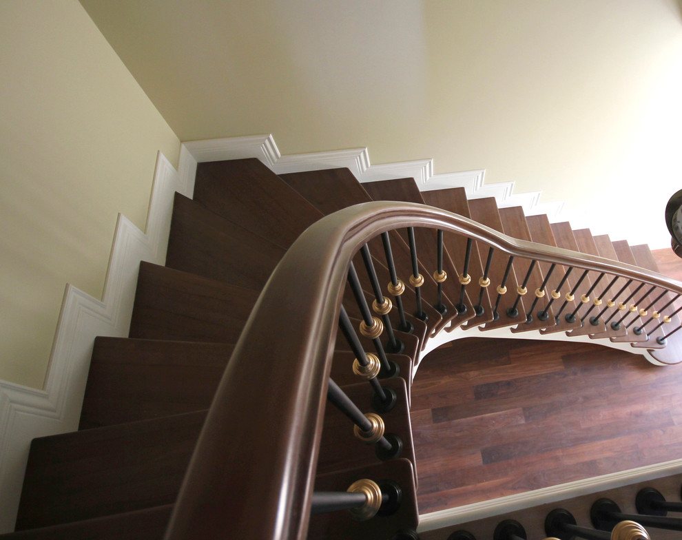 Ejemplo de escalera curva tradicional de tamaño medio con escalones de madera, contrahuellas de madera y barandilla de metal