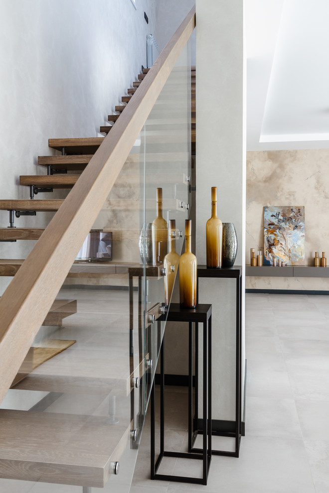 Стильный дизайн: большая прямая лестница в современном стиле с крашенными деревянными ступенями и стеклянными перилами - последний тренд