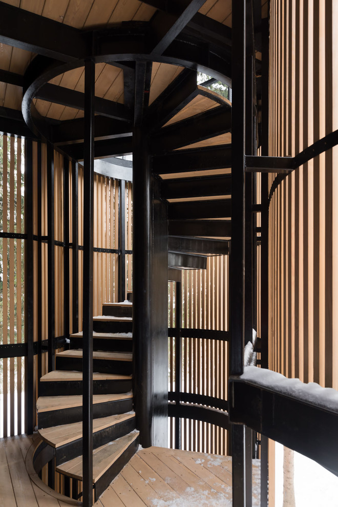На фото: винтовая металлическая лестница в современном стиле с деревянными ступенями и металлическими перилами с
