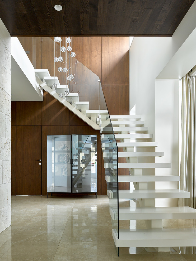 Пример оригинального дизайна: угловая лестница в современном стиле с стеклянными перилами без подступенок