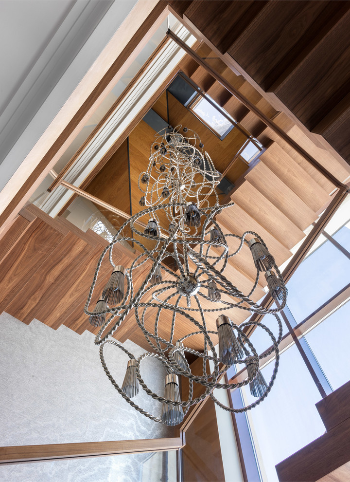 Imagen de escalera curva actual extra grande con escalones de madera, contrahuellas de madera y barandilla de vidrio
