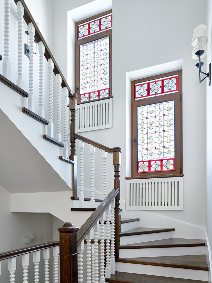 На фото: изогнутая лестница в современном стиле с деревянными ступенями и деревянными перилами