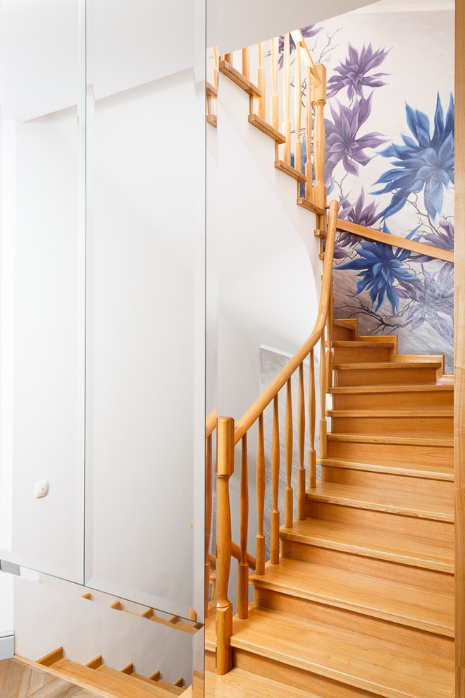 На фото: изогнутая деревянная лестница в скандинавском стиле с деревянными ступенями и деревянными перилами с