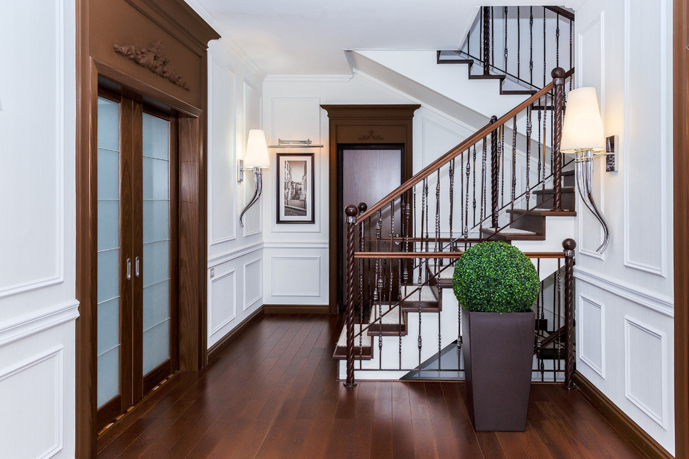 Imagen de escalera en U clásica de tamaño medio con escalones de madera, contrahuellas de madera y barandilla de metal