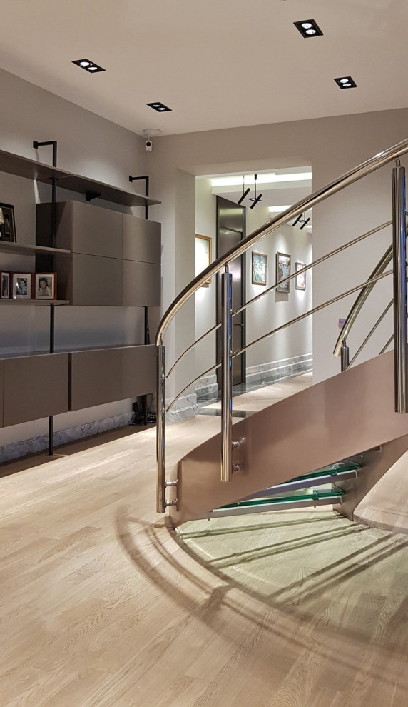 Cette image montre un escalier design avec des marches en verre et un garde-corps en métal.