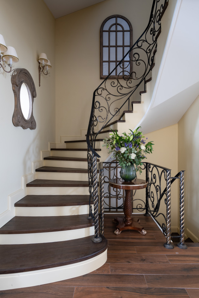 Пример оригинального дизайна: изогнутая лестница в современном стиле с деревянными ступенями и металлическими перилами