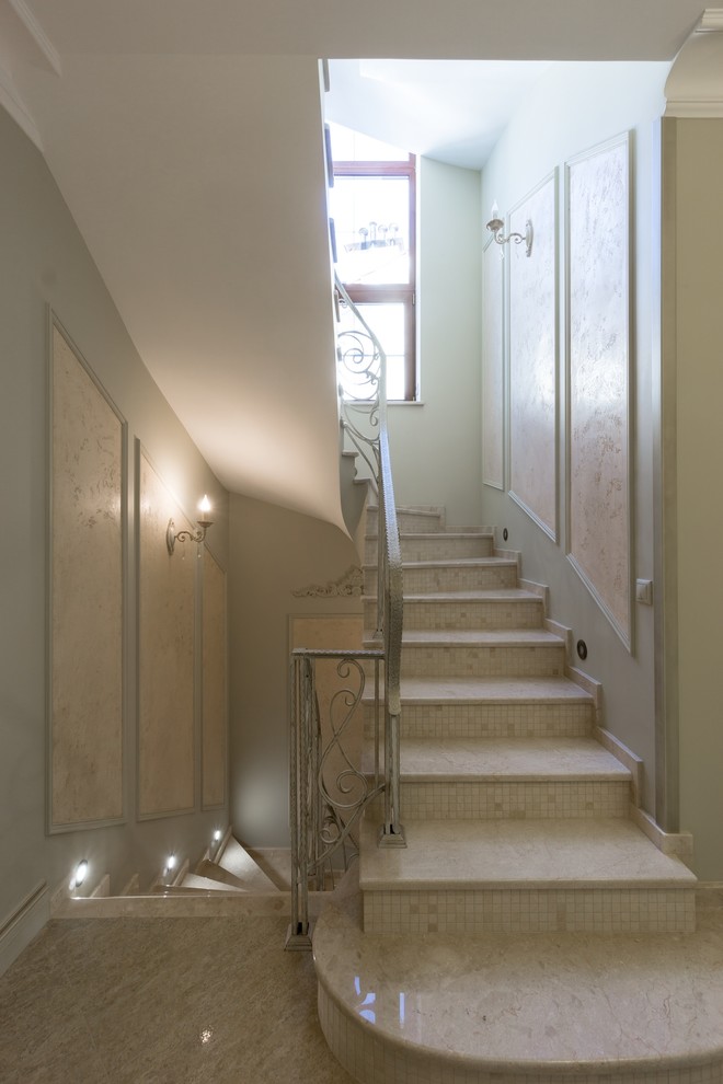 Exempel på en stor klassisk svängd trappa i marmor, med sättsteg i marmor och räcke i metall