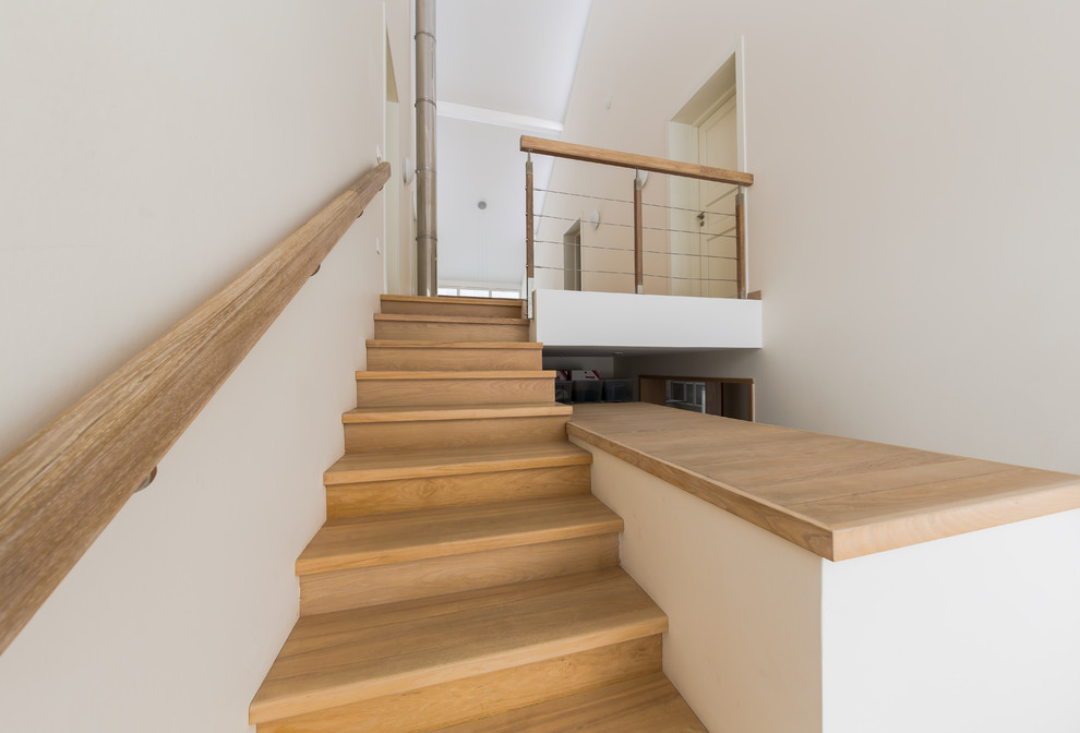 Пример оригинального дизайна: большая п-образная лестница в скандинавском стиле с крашенными деревянными ступенями и крашенными деревянными подступенками