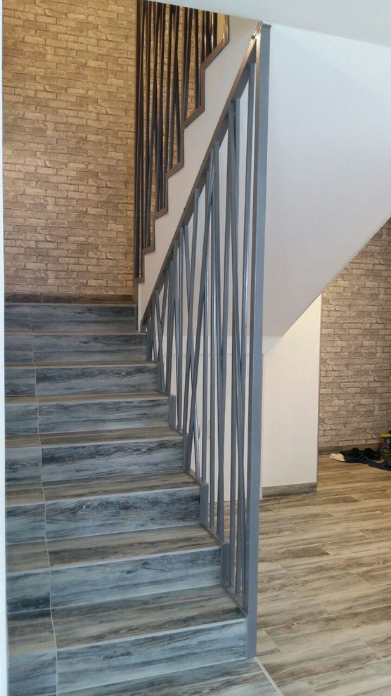 エカテリンブルクにあるお手頃価格の広いコンテンポラリースタイルのおしゃれな直階段 (タイルの蹴込み板、金属の手すり) の写真