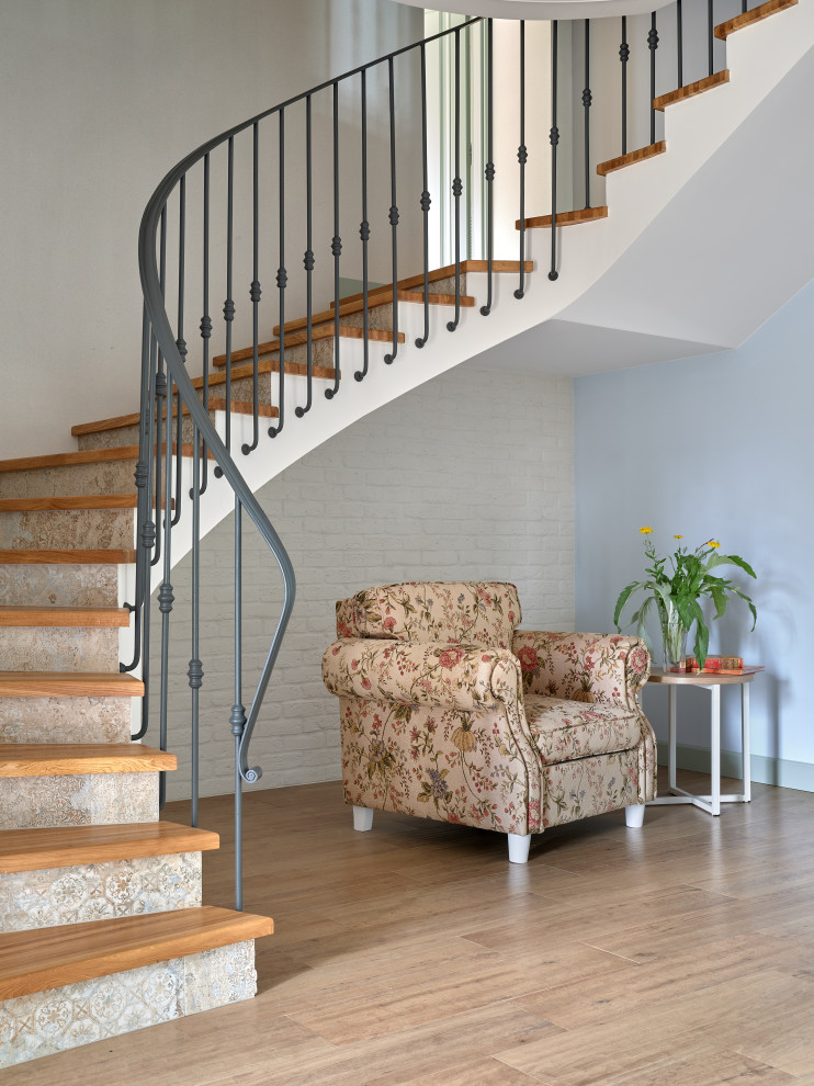 Idées déco pour un escalier courbe classique avec des marches en bois, des contremarches carrelées et un garde-corps en métal.