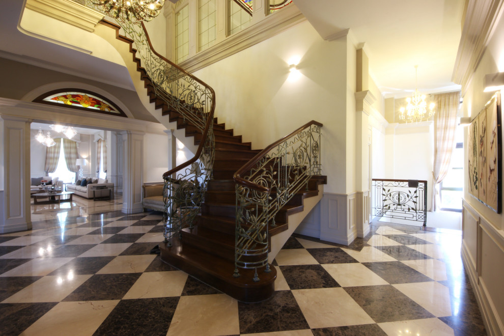 Inspiration pour un grand escalier traditionnel en U avec des marches en bois, des contremarches en bois, un garde-corps en métal et du lambris.