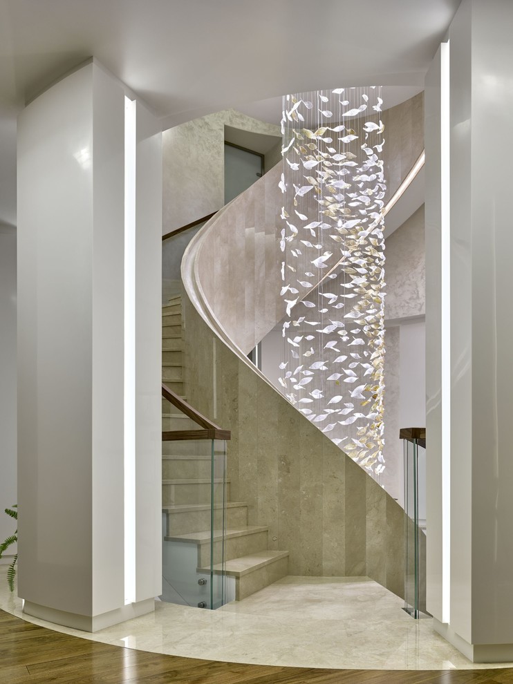 На фото: большая винтовая лестница в современном стиле с мраморными ступенями, подступенками из мрамора и перилами из смешанных материалов