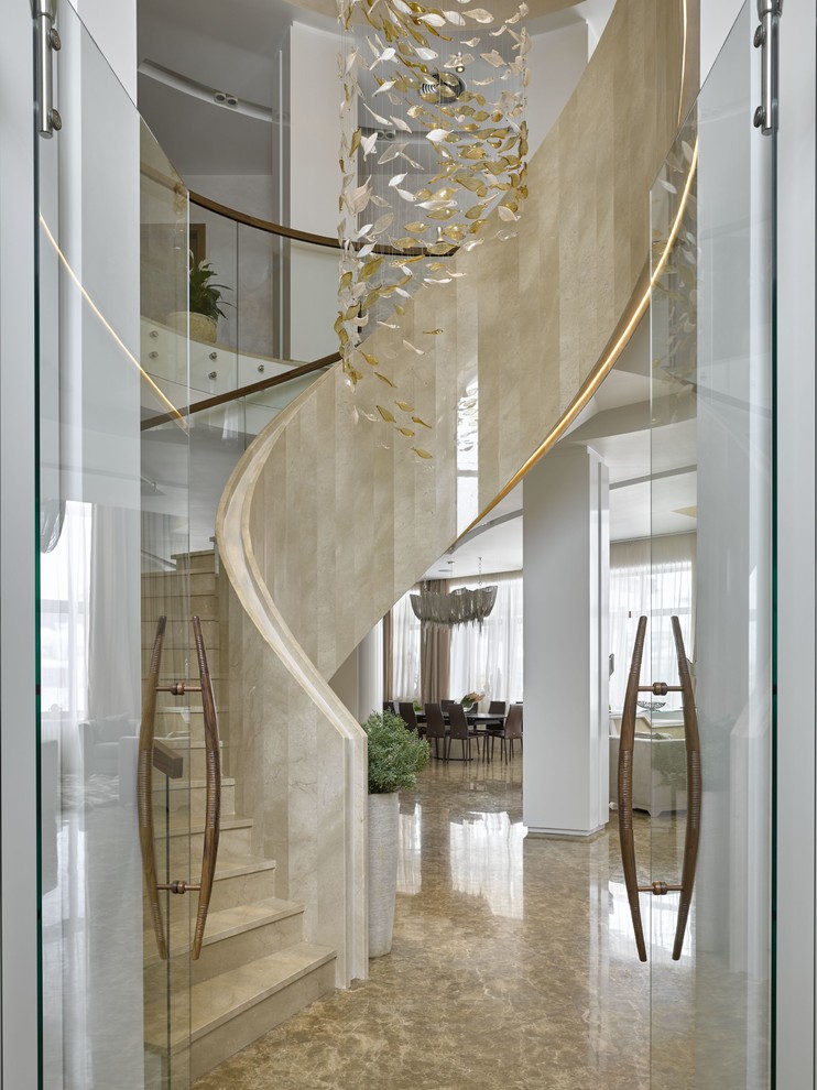 На фото: большая винтовая лестница в современном стиле с мраморными ступенями, подступенками из мрамора и перилами из смешанных материалов с