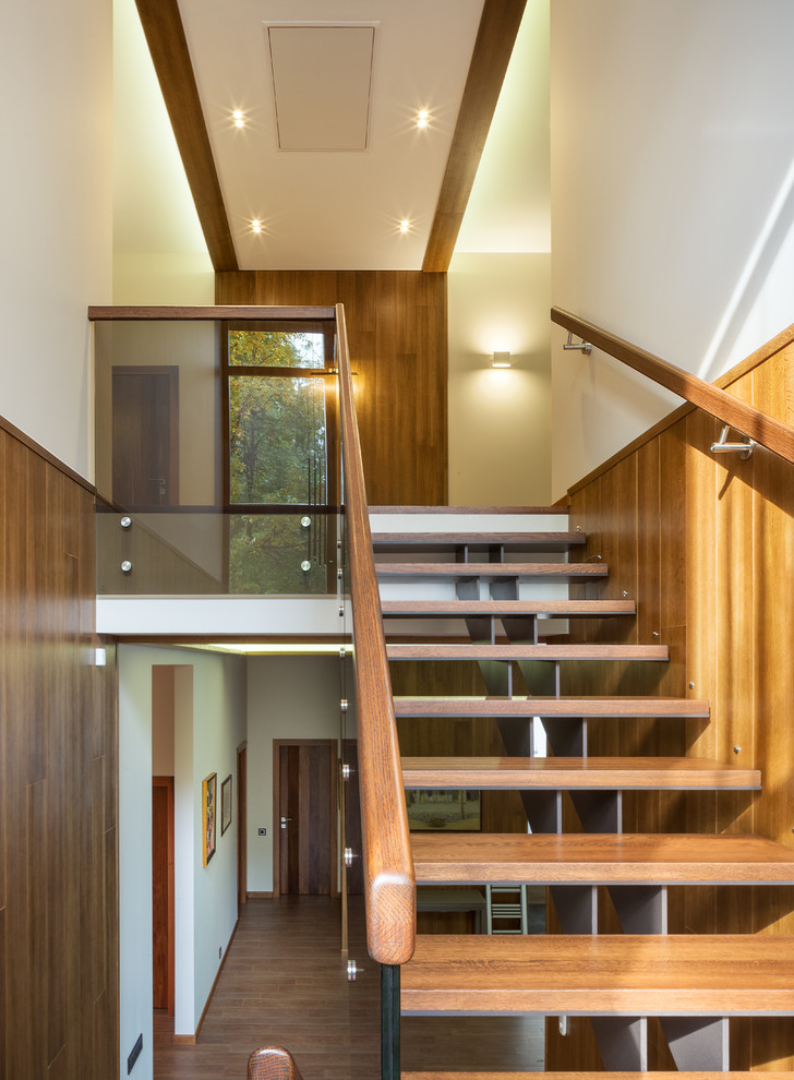 Идея дизайна: угловая металлическая лестница среднего размера с деревянными ступенями, деревянными перилами и панелями на части стены