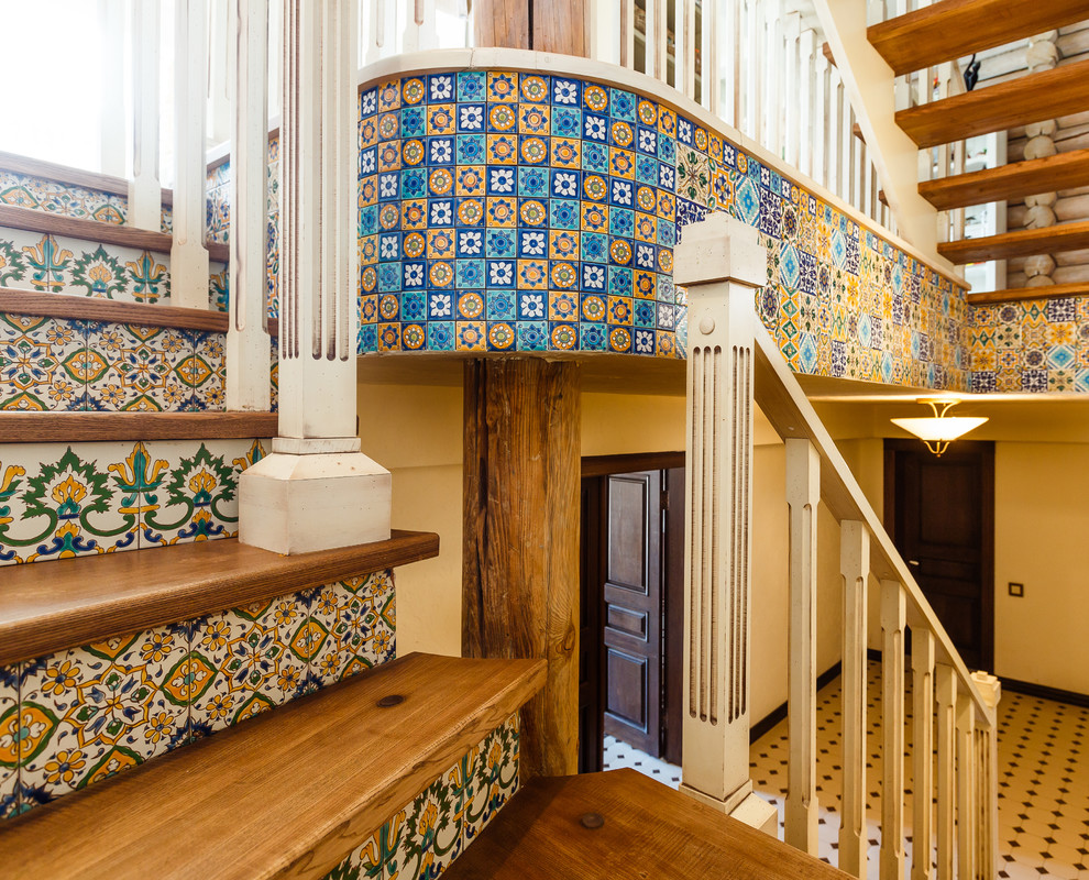 Пример оригинального дизайна: изогнутая лестница в стиле кантри с деревянными ступенями, подступенками из плитки и деревянными перилами