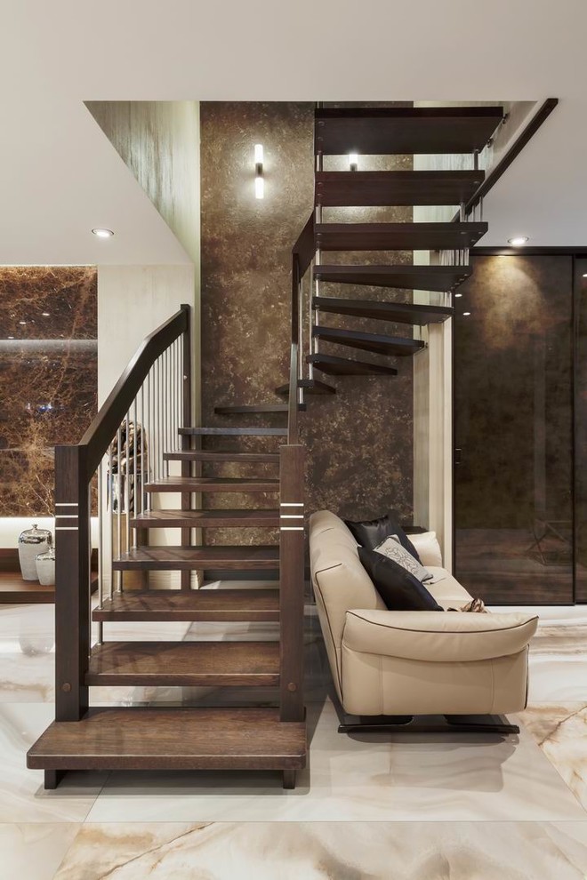 На фото: большая изогнутая лестница в современном стиле с деревянными ступенями и перилами из смешанных материалов без подступенок с