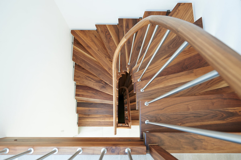 Ejemplo de escalera curva nórdica con escalones de madera y barandilla de madera