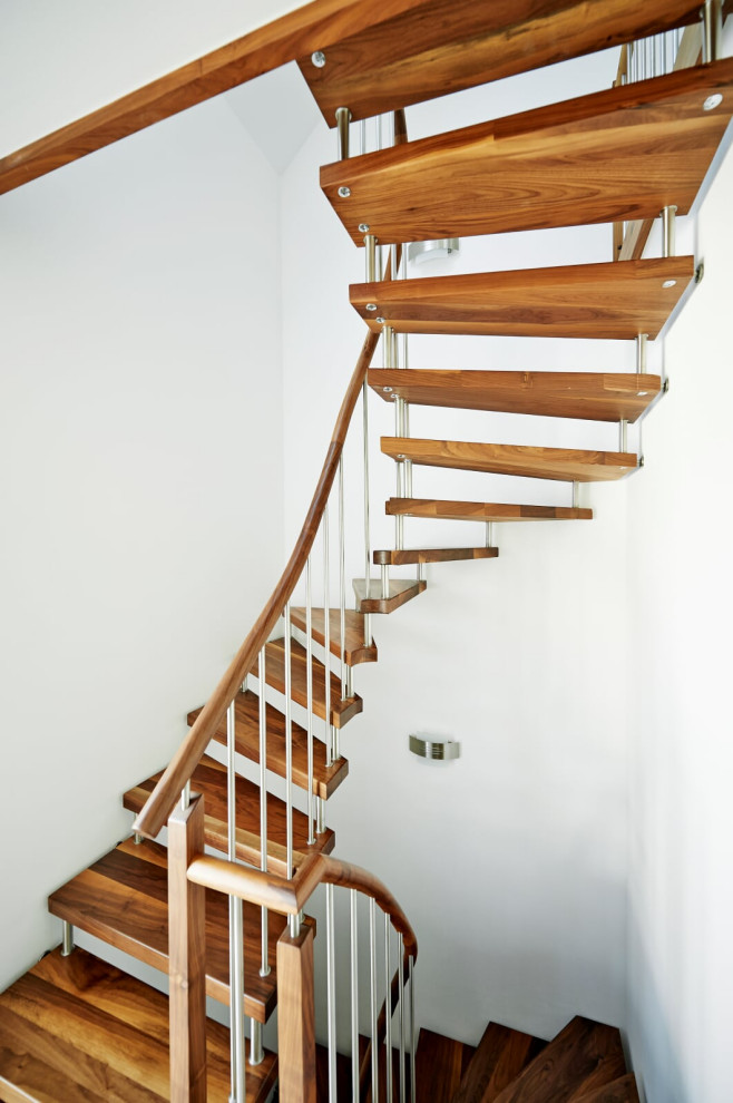 На фото: изогнутая лестница в скандинавском стиле с деревянными ступенями и деревянными перилами