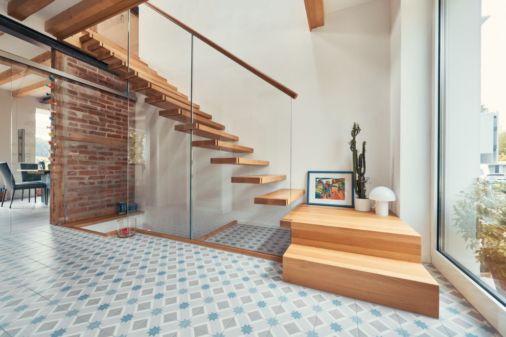 Foto på en minimalistisk l-trappa i trä, med räcke i flera material och öppna sättsteg