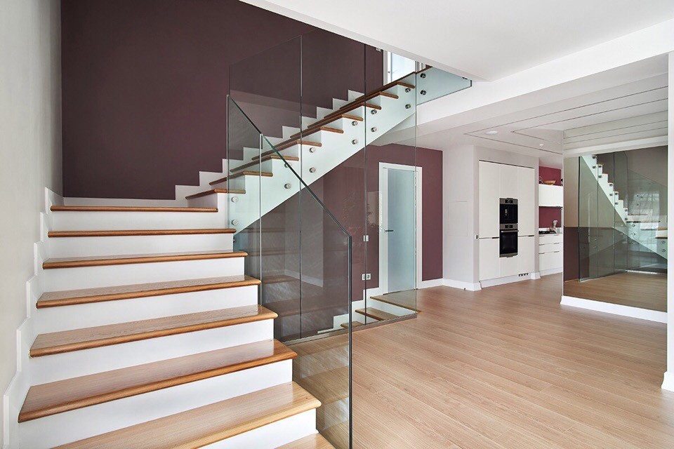 Aménagement d'un grand escalier contemporain en L avec des marches en bois, des contremarches en bois et un garde-corps en verre.