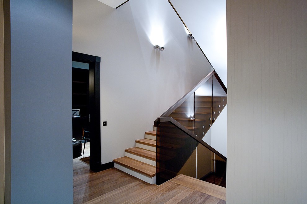 Пример оригинального дизайна: большая п-образная бетонная лестница в современном стиле с деревянными ступенями и стеклянными перилами