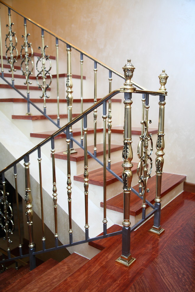 Diseño de escalera en U clásica grande con escalones de madera, contrahuellas de hormigón y barandilla de metal