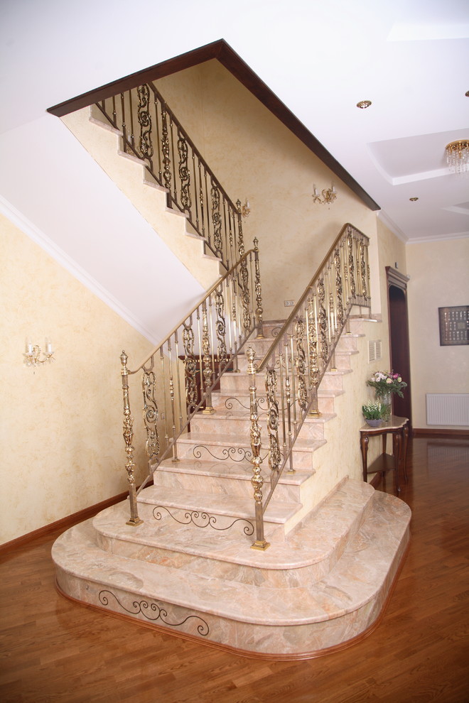 Inspiration for a large classic curved metal railing staircase in Moscow with marble treads and marble risers.