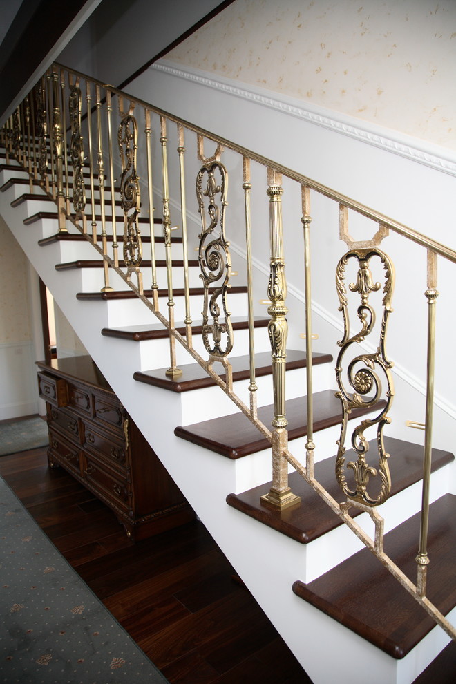 Aménagement d'un grand escalier droit classique avec des marches en bois, des contremarches en béton et un garde-corps en métal.