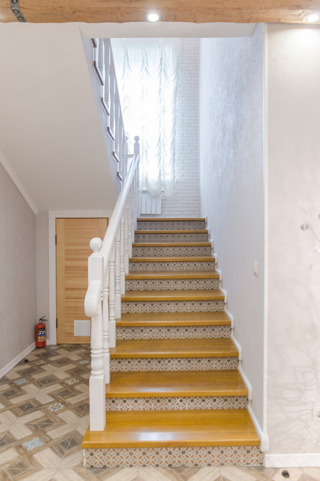 Свежая идея для дизайна: большая угловая лестница в стиле неоклассика (современная классика) с деревянными ступенями и подступенками из плитки - отличное фото интерьера