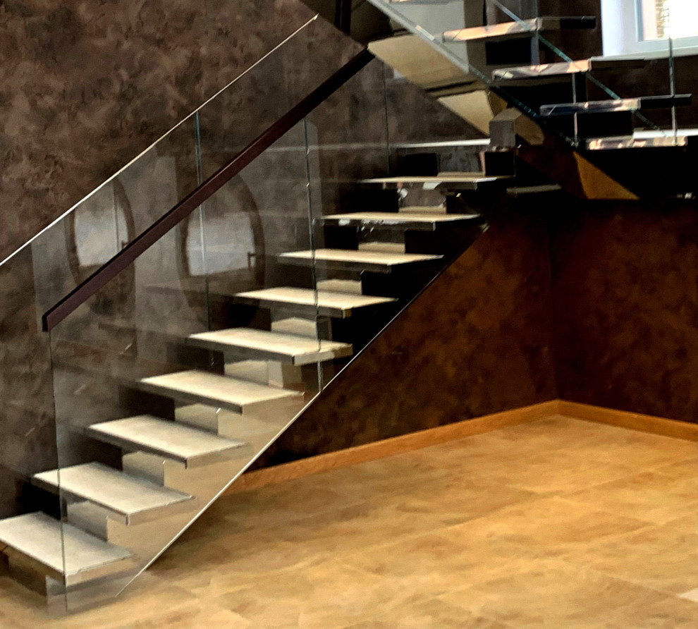 Cette photo montre un escalier chic en U avec des marches en bois et un garde-corps en verre.