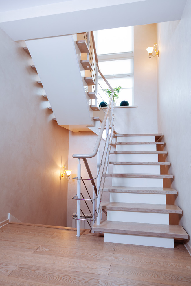 Modelo de escalera en U actual pequeña con escalones de madera, contrahuellas de madera pintada y barandilla de metal