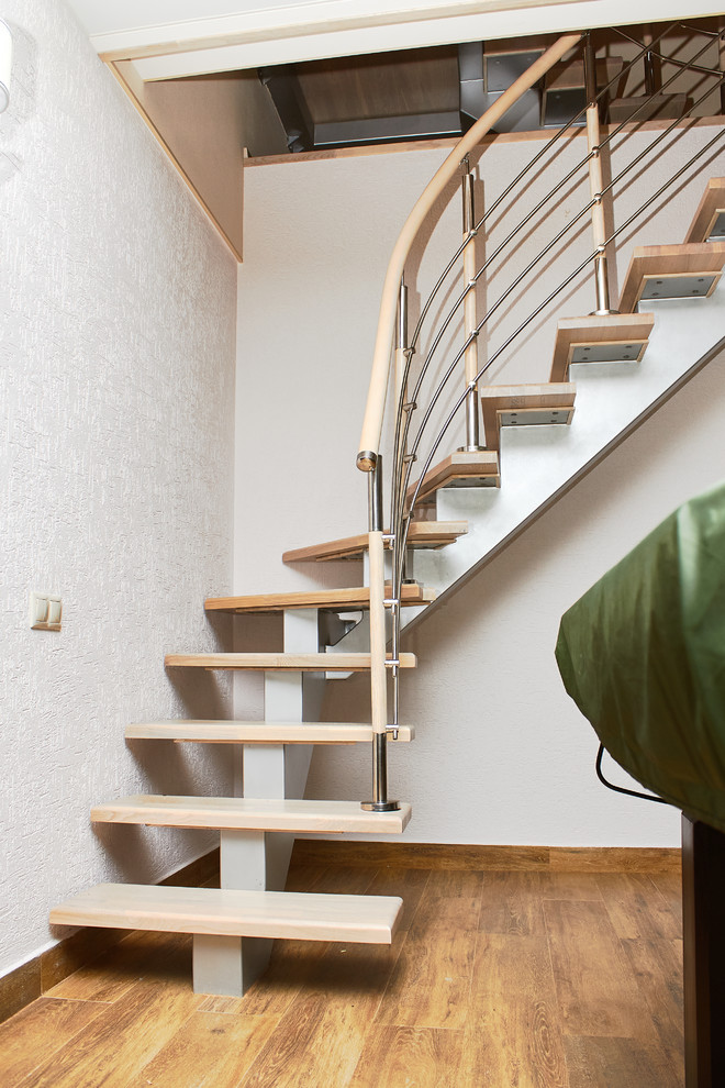 На фото: изогнутая лестница с деревянными ступенями и перилами из смешанных материалов