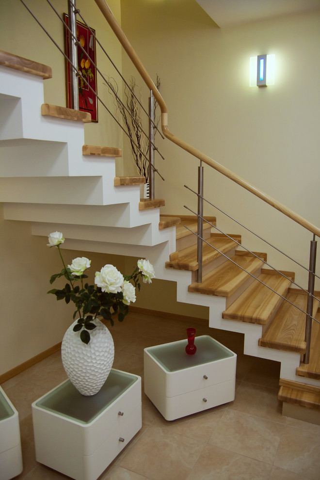 На фото: угловая деревянная лестница среднего размера в современном стиле с деревянными ступенями и деревянными перилами с