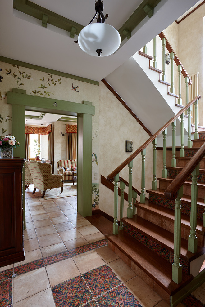 Ejemplo de escalera en U de estilo de casa de campo con escalones de madera, contrahuellas con baldosas y/o azulejos y barandilla de madera