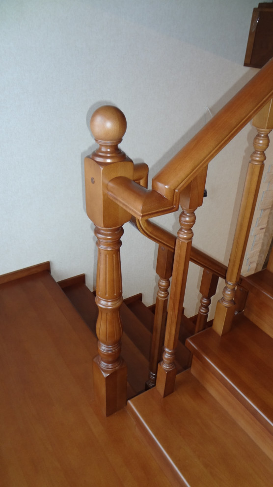 Large wood u-shaped wood railing staircase in Other with wood risers.