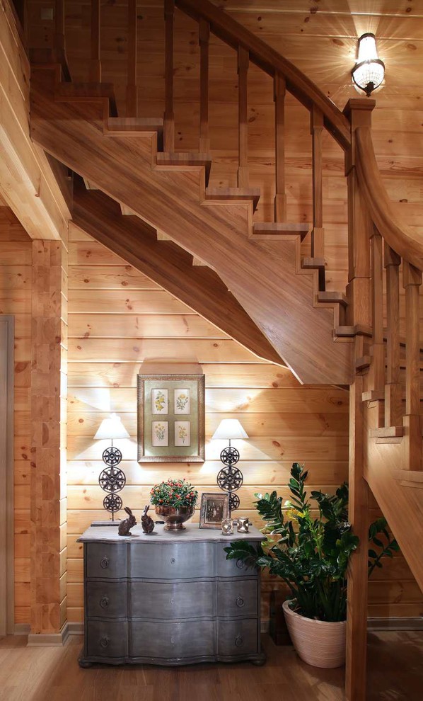 На фото: большая угловая деревянная лестница в стиле кантри с деревянными ступенями и деревянными перилами