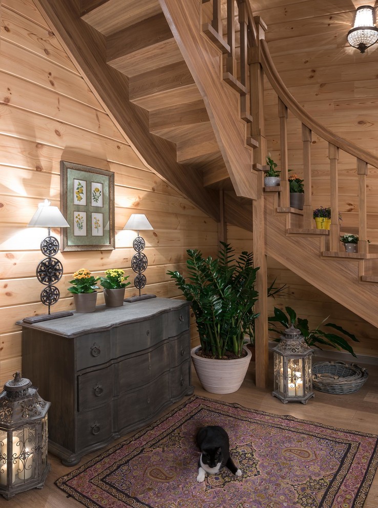 На фото: большая п-образная деревянная лестница в стиле кантри с деревянными ступенями и деревянными перилами с