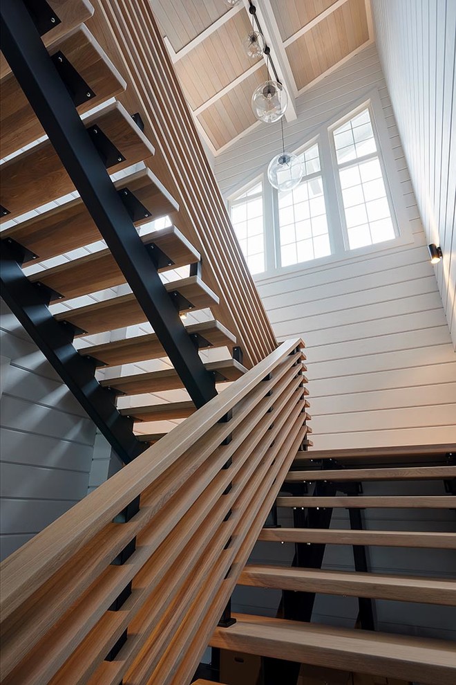 Aménagement d'un grand escalier contemporain en U avec des marches en bois et un garde-corps en bois.