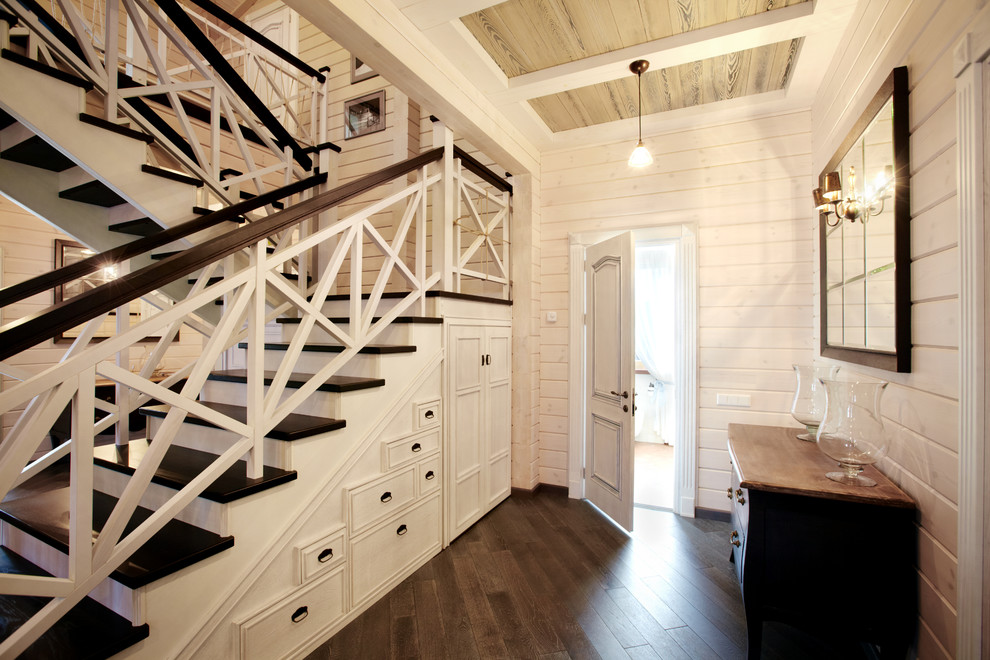 Diseño de escalera en U de estilo de casa de campo grande con escalones de madera, contrahuellas de madera y barandilla de madera