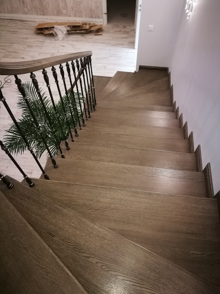 Exemple d'un grand escalier courbe éclectique avec des marches en bois, des contremarches en bois et un garde-corps en matériaux mixtes.