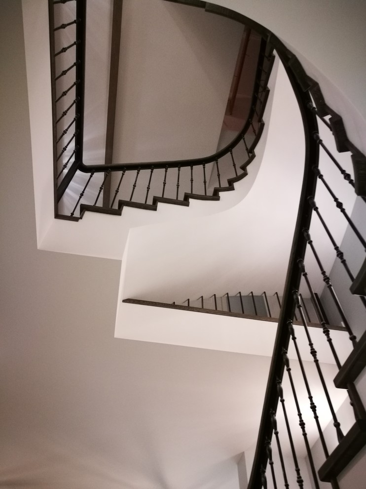 Cette photo montre un grand escalier courbe éclectique avec des marches en bois, des contremarches en bois et un garde-corps en matériaux mixtes.