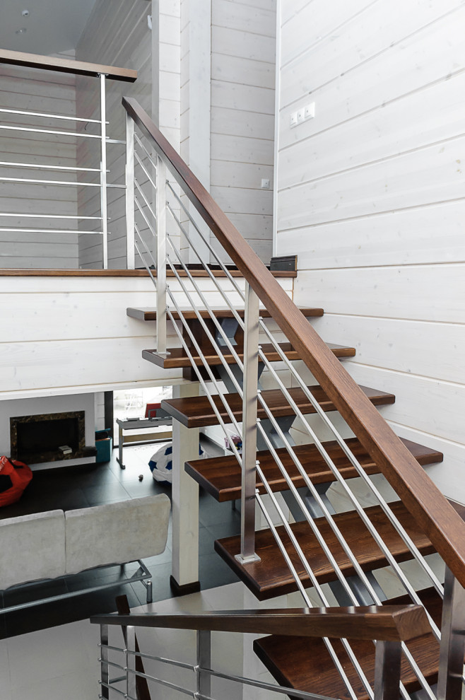 На фото: п-образная лестница среднего размера в стиле лофт с деревянными ступенями, металлическими перилами и деревянными стенами без подступенок