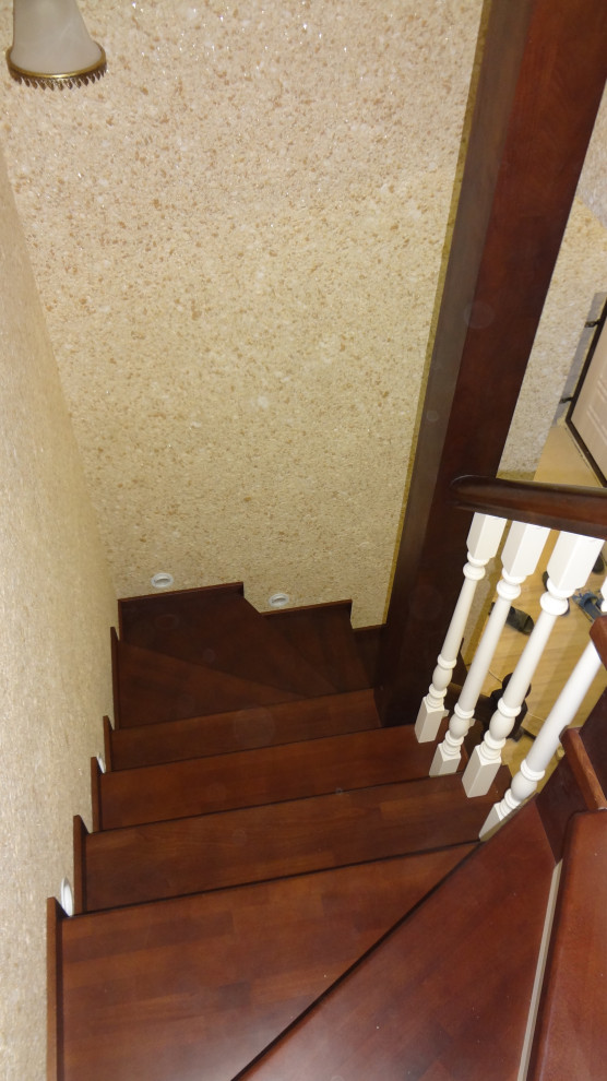 Imagen de escalera en U grande con escalones de madera, contrahuellas de madera y barandilla de madera