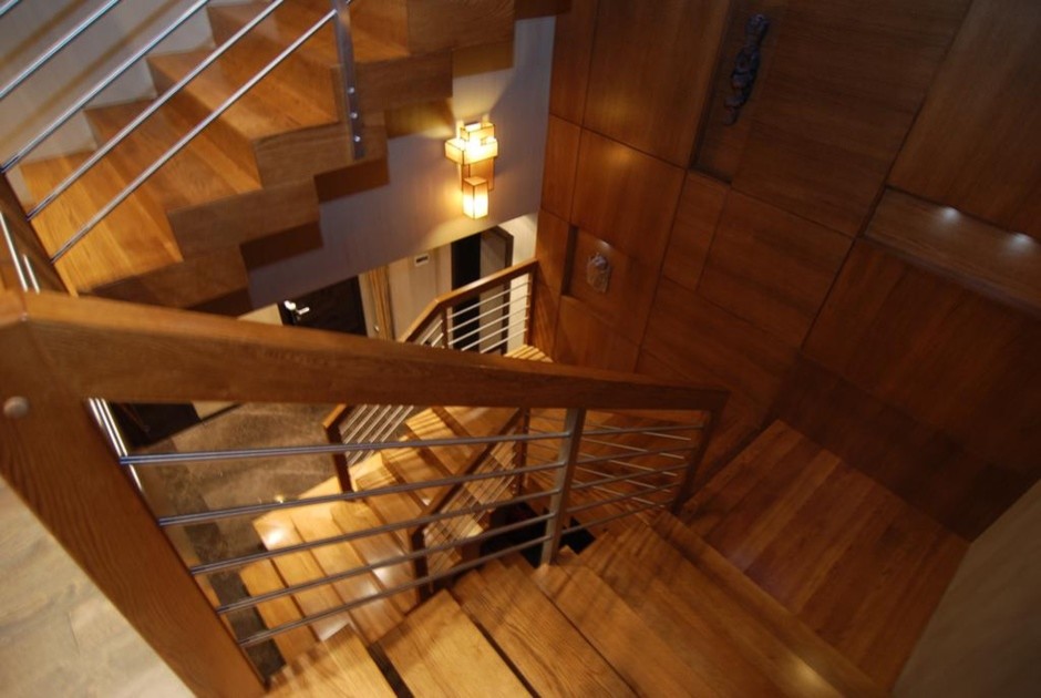 На фото: большая п-образная деревянная лестница в стиле неоклассика (современная классика) с деревянными ступенями и деревянными перилами с
